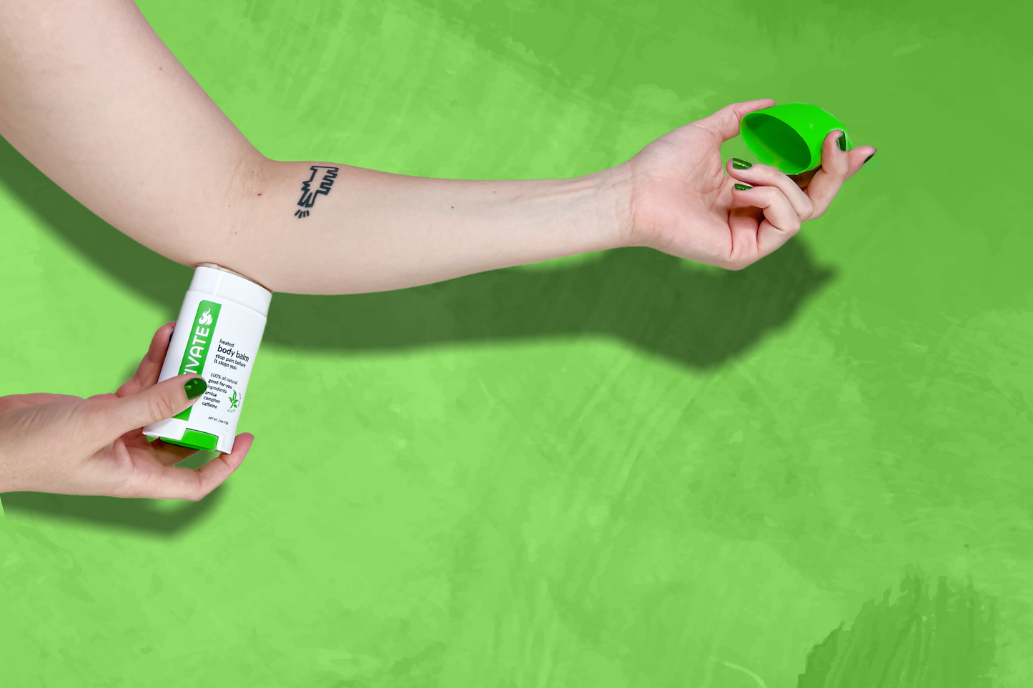 caucasian female with keith haring dog tattoo applying a green and white, "activate pain relief body balm" onto a sore elbow prior to activity to prevent further injury.