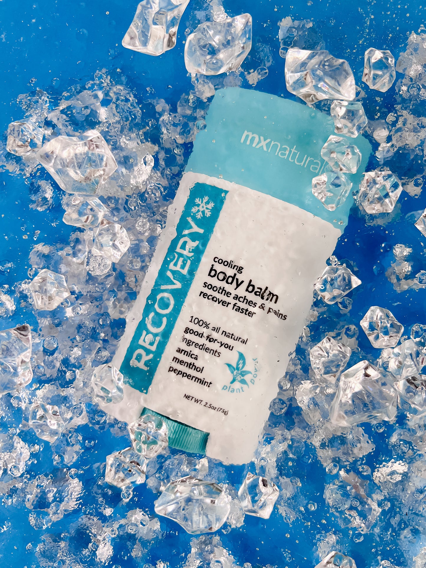 a white and blue product titled "recovery cooling body care balm"  is submerged under ice cold water to represent the chill of the product on a blue background.